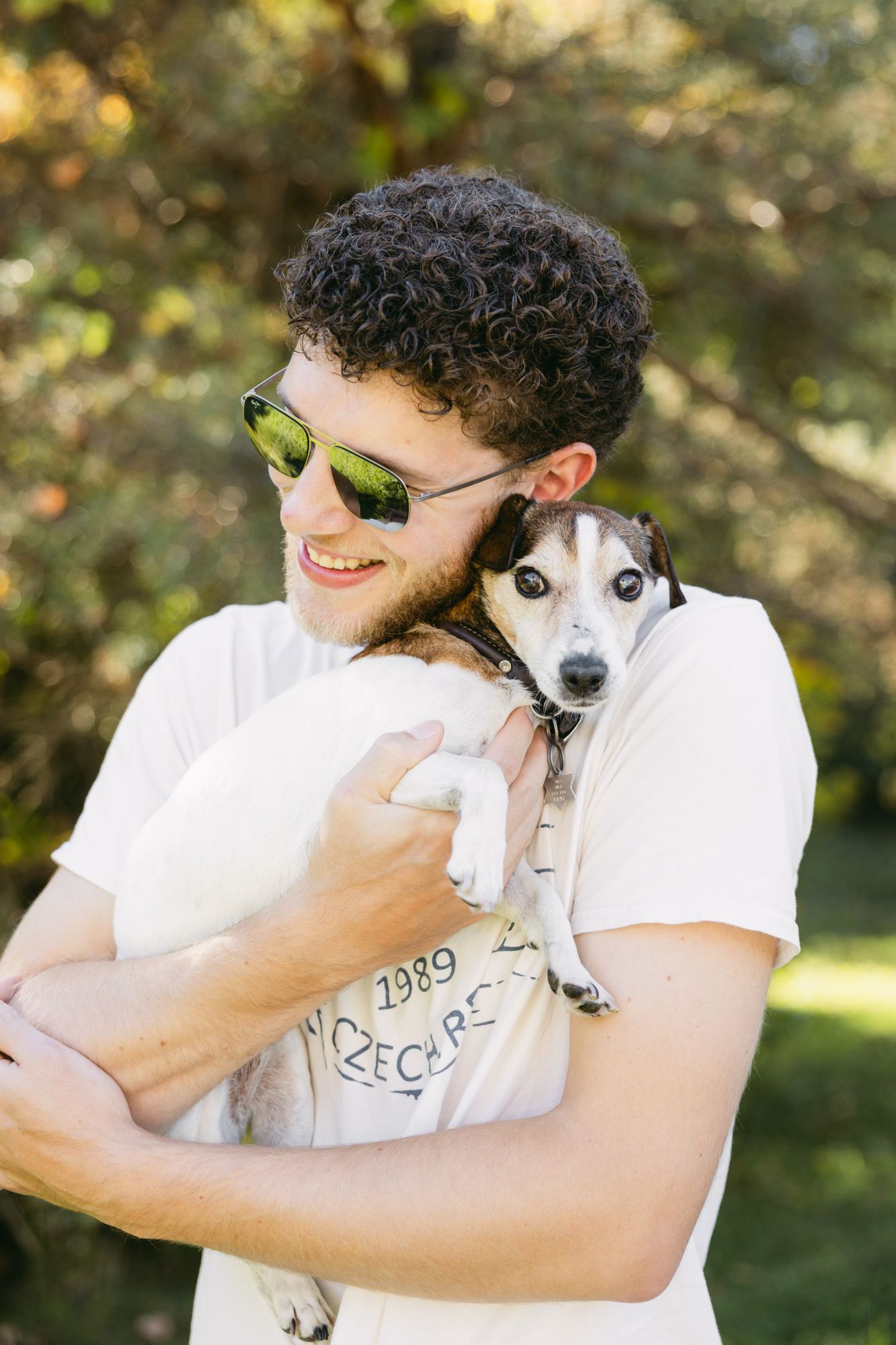 A young man holding his Jack Russell terrier close